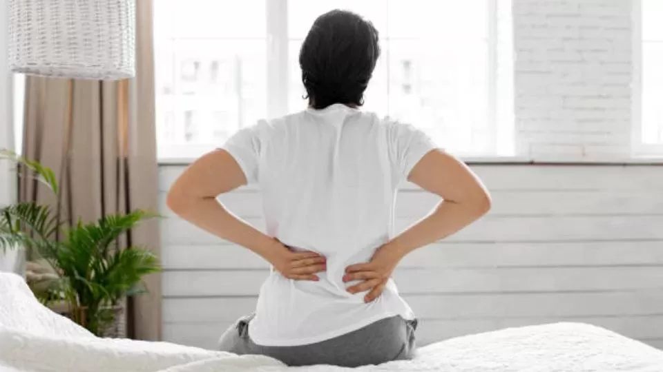 An Individual Sitting On Mattress Suffering From Back Pain