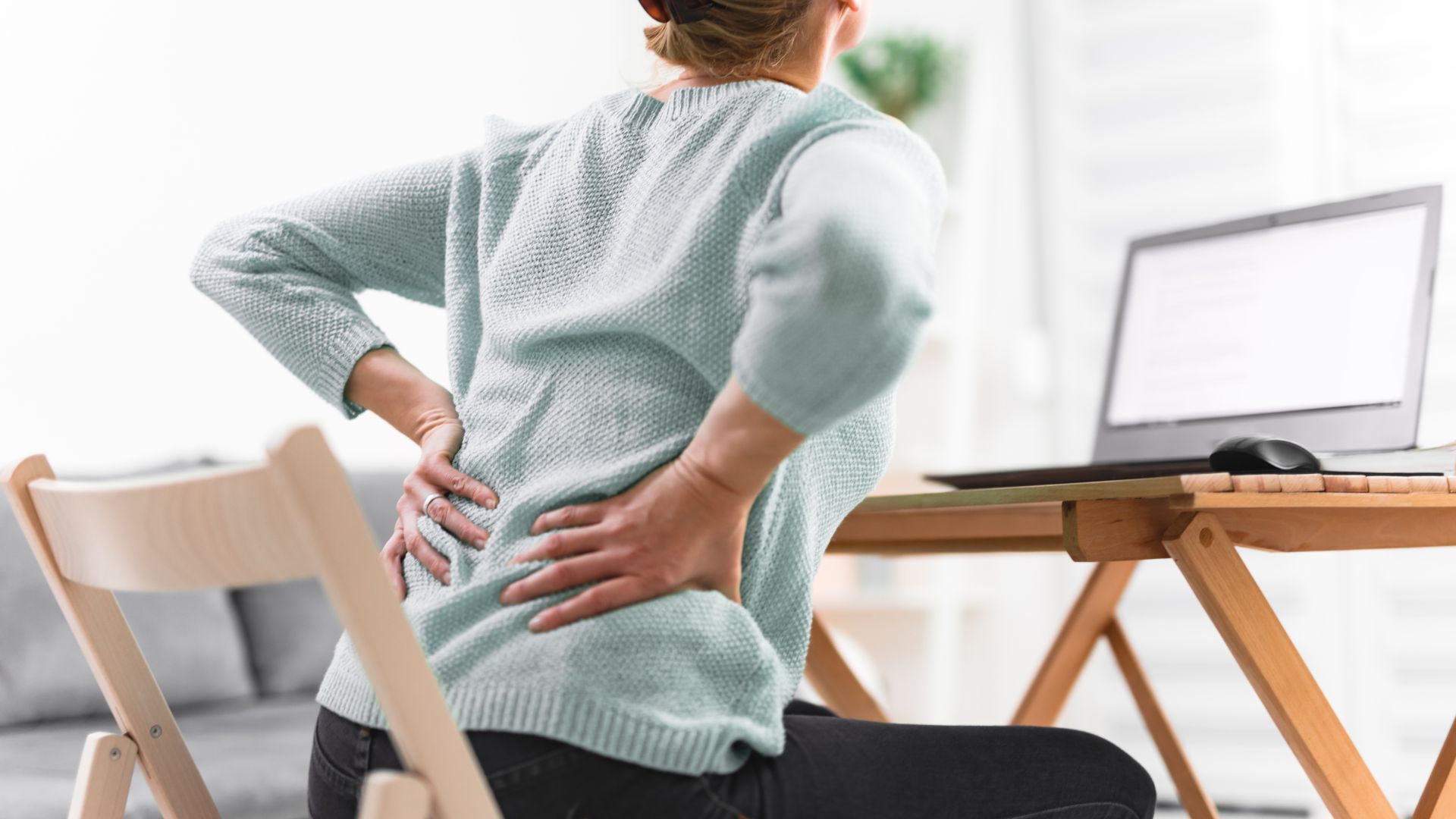 Woman Experiencing Hip Pain While Sitting In Front Of Laptop